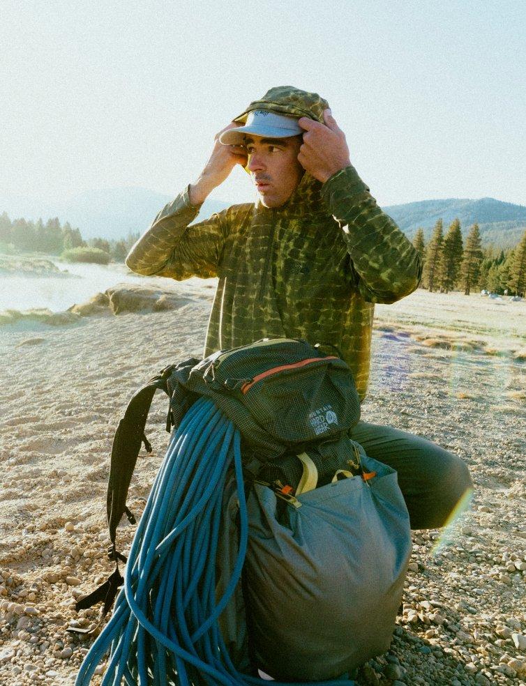 A climber gets ready for his approach, adjusting helmet, getting ready to put on backpack.