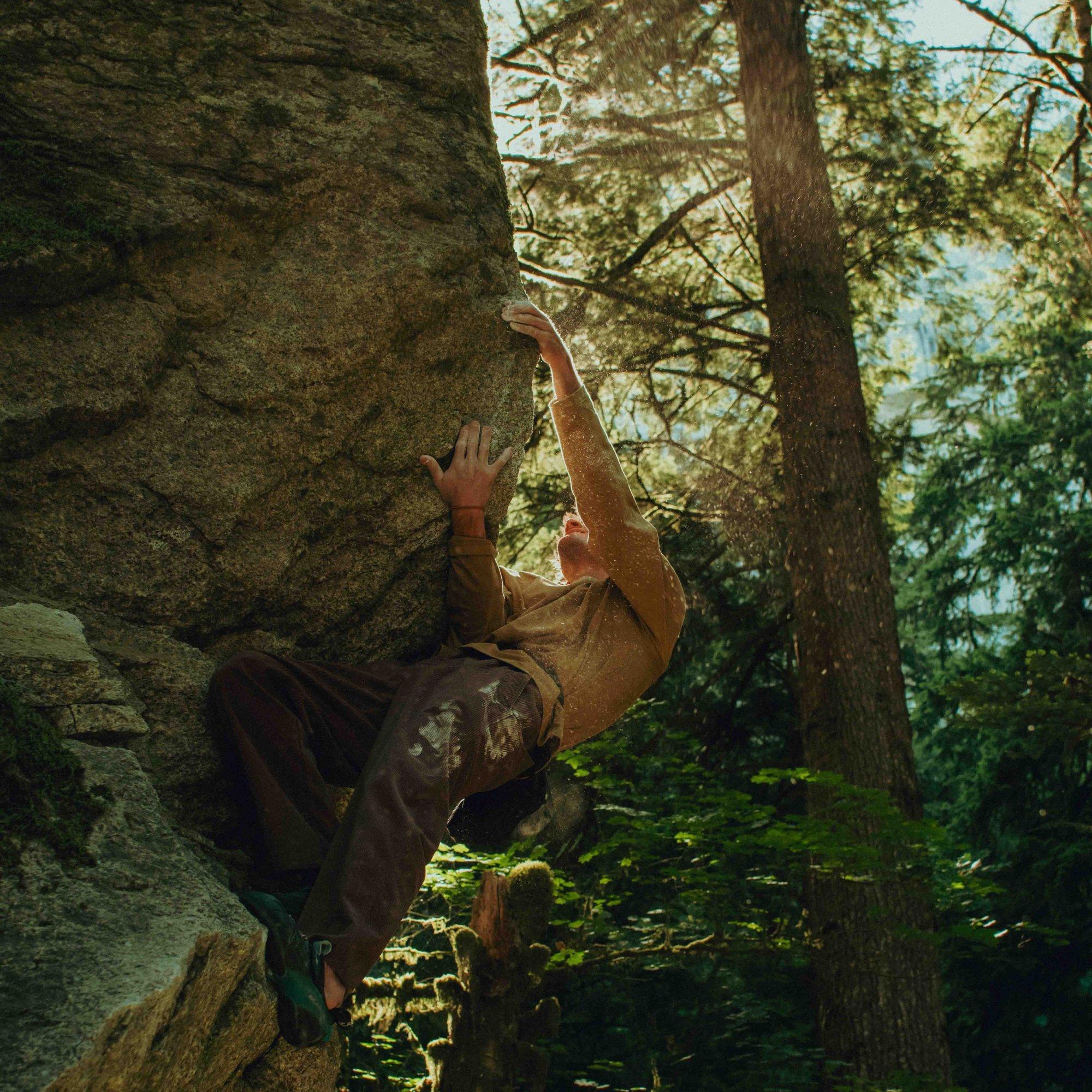 Chalk flies as a boulderer in a Hardwear Supply™ Long Sleeve leans into an underhand grip, grimacing.