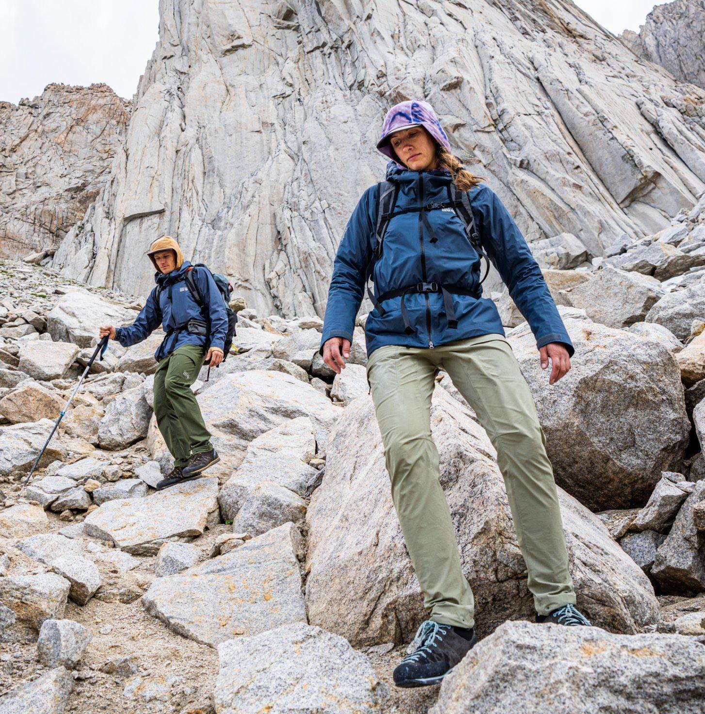 Two alpinists in Chockstone™ jackets and pants traverse down jagged rocks.